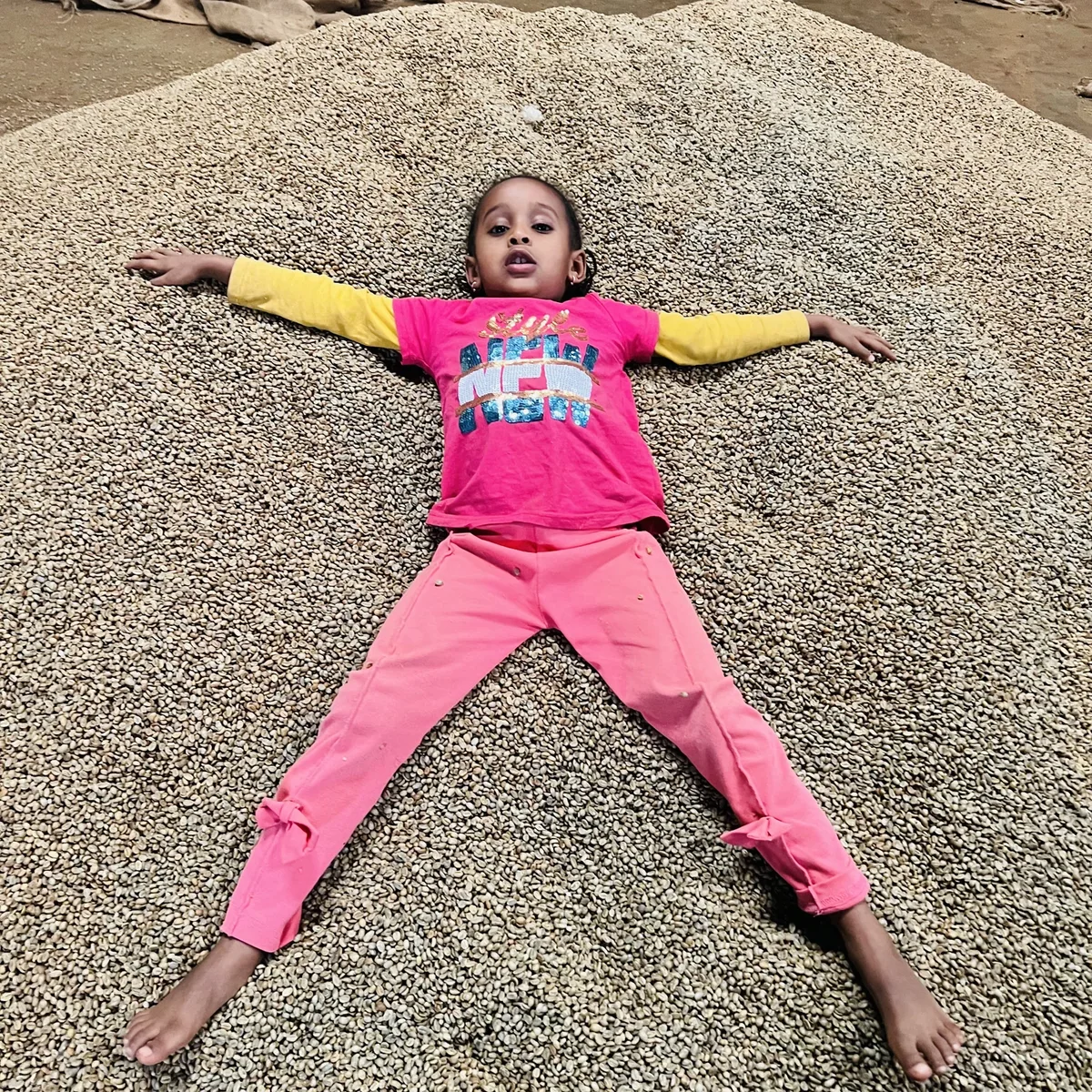 A child on a mountain of coffee beans